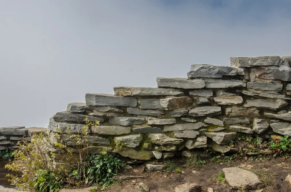 Pared de piedra apilada con fondo nublado — Foto de Stock