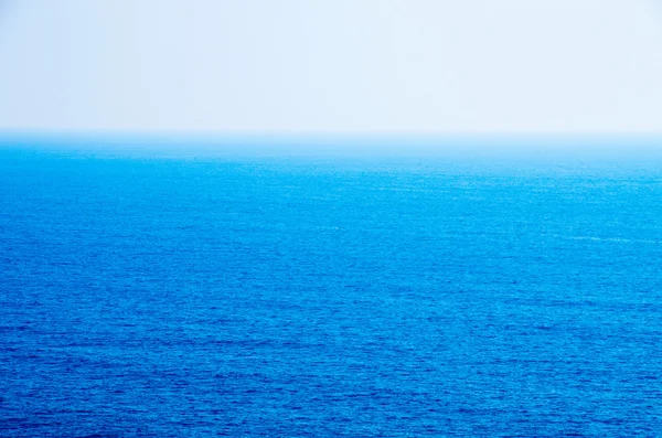 Modré moře s vlnami a jasnou modrou oblohou — Stock fotografie