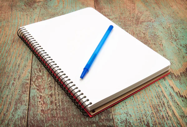 spiral notebook and pen on wooden desk