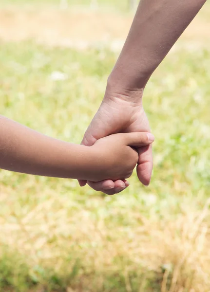 Ibu memegang tangan anaknya di hari musim panas di luar ruangan — Stok Foto