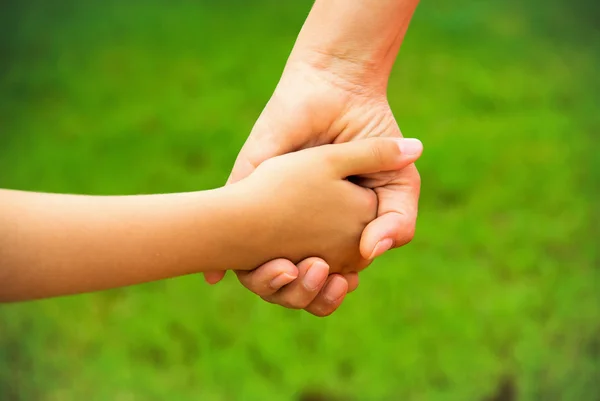 Anne, yaz günü açık havada oğlunun elini tutuyor.