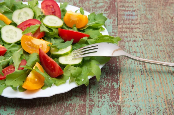 Green salad made with arugula, tomatoes, cheese mozzarella balls and sesame on plate — Stock Photo, Image