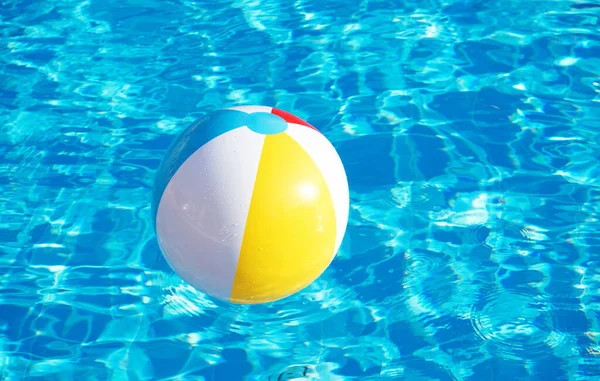 Un Ballon De Football Flottant Dans Une Piscine Avec De L'eau Et Le Soleil  Se Reflétant Au Fond.