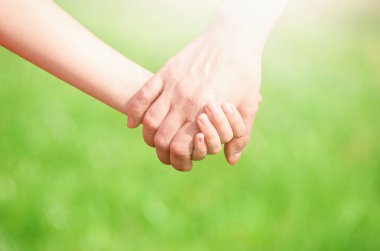 Anne, yaz günü açık havada oğlunun elini tutuyor.