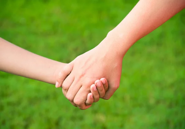 Anne, yaz günü açık havada oğlunun elini tutuyor.