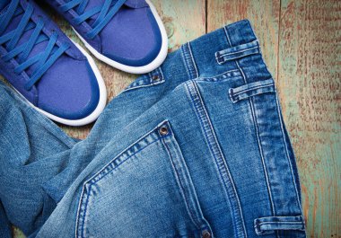 Yere atılmış bir çift kot ve bir çift spor ayakkabı.