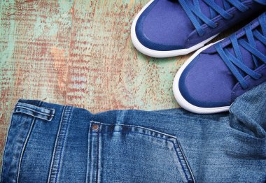 Yere atılmış bir çift kot ve bir çift spor ayakkabı.