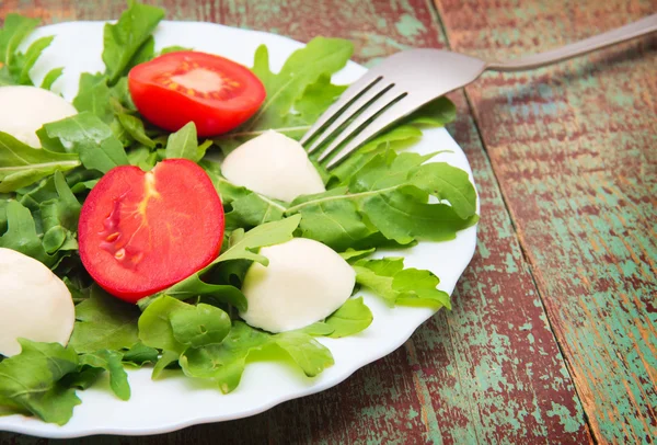 Green salad made with arugula, tomatoes, cheese mozzarella — Stock Photo, Image