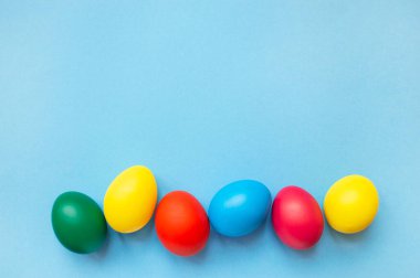 Mavi arka planda renkli paskalya yumurtaları ve fotokopi alanı. Paskalya arkaplanı