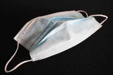 Siyah arka planda cerrahi maske kullanılmış. Çöpe atılmış maske konsepti Corona virüsü, covid-19.