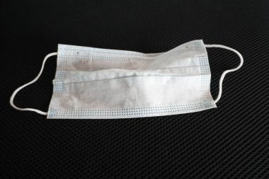 Siyah arka planda cerrahi maske kullanılmış. Çöpe atılmış maske konsepti Corona virüsü, covid-19.