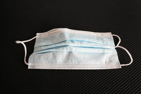 Siyah arka planda cerrahi maske kullanılmış. Çöpe atılmış maske konsepti Corona virüsü, covid-19.