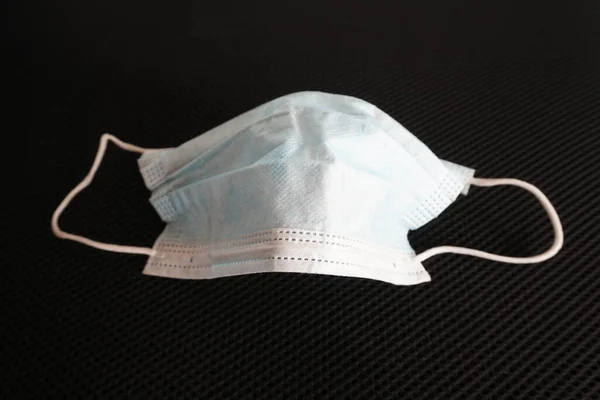 Siyah arka planda cerrahi maske kullanılmış. Çöpe atılmış maske konsepti Corona virüsü, covid-19.