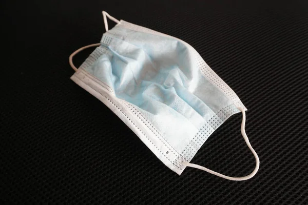 Siyah arka planda cerrahi maske kullanılmış. Çöpe atılmış maske konsepti Corona virüsü, covid-19.