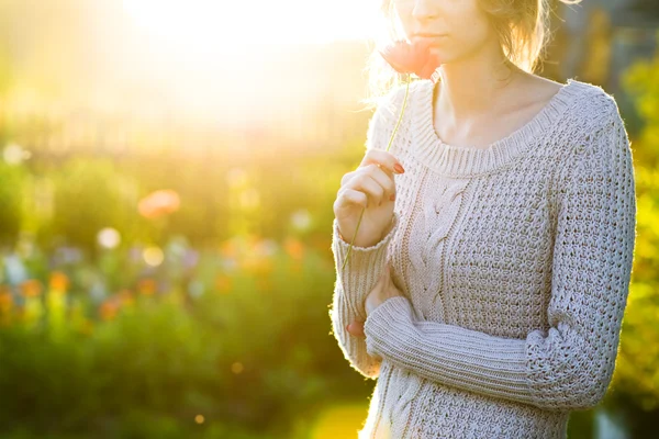 Akşam güneş ışığında bir haşhaş çiçek tutan genç kadın. — Stok fotoğraf