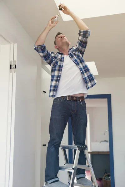 Man changing a lightbulb in living room — Stock Photo, Image