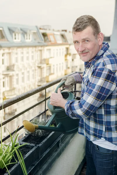 Muž zalévání rostlin na balkóně — Stock fotografie