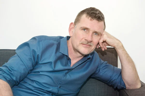 Portrait of handsome mature man sitting on couch — Stock Photo, Image