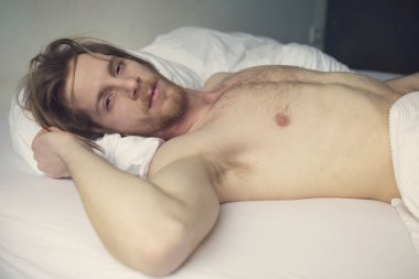 Kızıl saçlı genç adam yatakta yatan