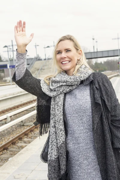 Retrato de mulher cumprimentando alguém na estação de trem — Fotografia de Stock