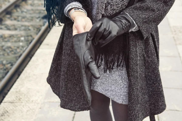 Primer plano de la mujer en la estación de tren ponerse los guantes — Foto de Stock