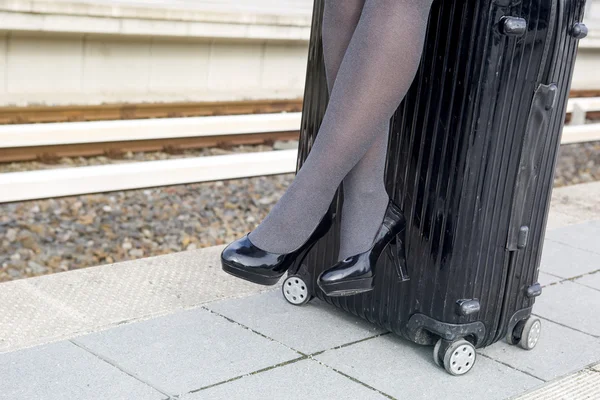 Close-up of woman sitting on suitcase at train station — Stock Photo, Image