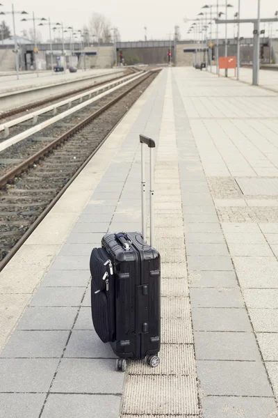 Maleta negra en la plataforma en una estación de tren — Foto de Stock