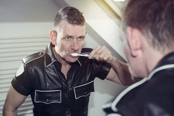 Muž v fetiš kožený ohoz čistit si zuby — Stock fotografie