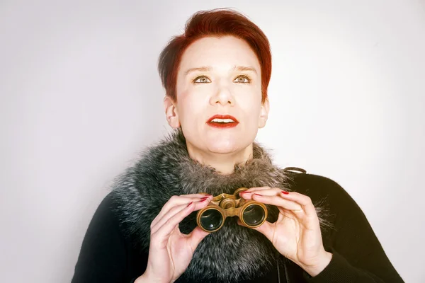 Woman with red hair looking through binoculars — Stock Photo, Image