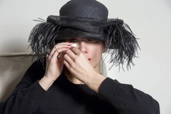 Portret van een vrouw met zwarte jurk en muts op zoek triest — Stockfoto