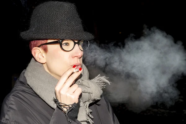 Woman with hat and glasses smoking a cigarette — Stock Photo, Image