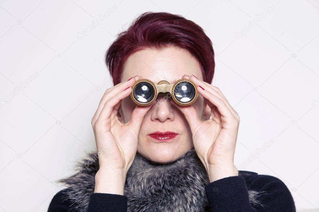 woman with red hair looking through binoculars