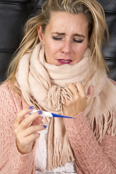 Mujer teniendo un resfriado y mirando el termómetro —  Fotos de Stock