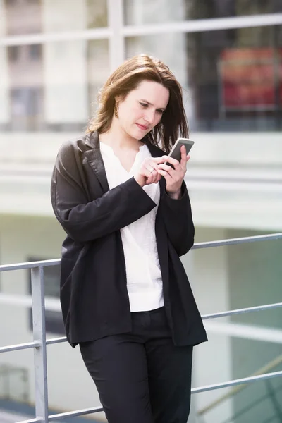 Jeune femme debout dehors et textos au téléphone — Photo