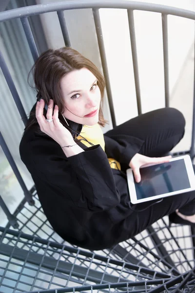 Jonge vrouw met hoofdtelefoon en ebook — Stockfoto