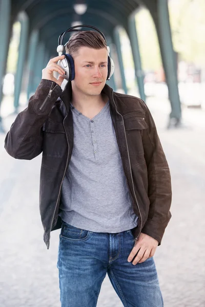 Junger Mann mit Kopfhörern steht auf der Straße — Stockfoto