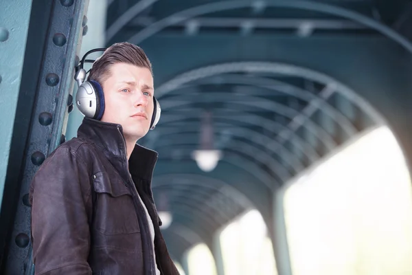 Young man with headphones standing in the street — Stock Photo, Image