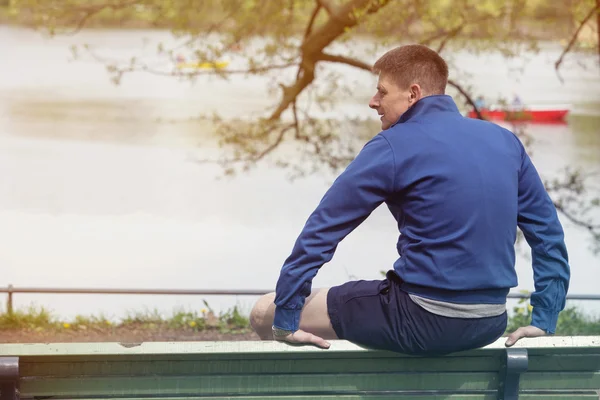 Man sitting on bench and looking at a lake — Stock Photo, Image