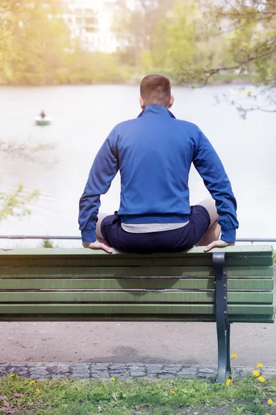 Homem sentado no banco e olhando para um lago — Fotografia de Stock