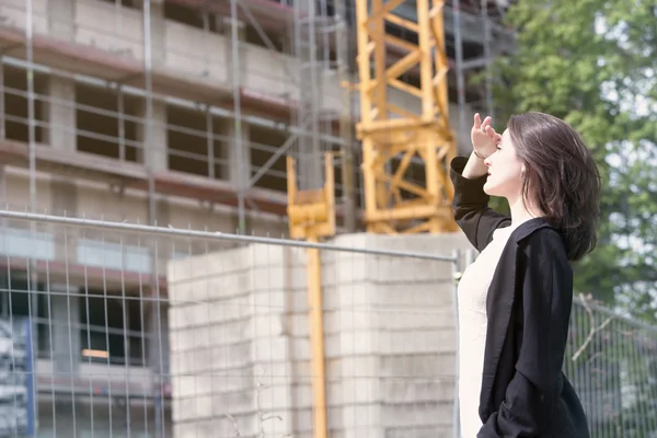 Vrouw permanent op de bouwplaats en kijken naar gebouw — Stockfoto