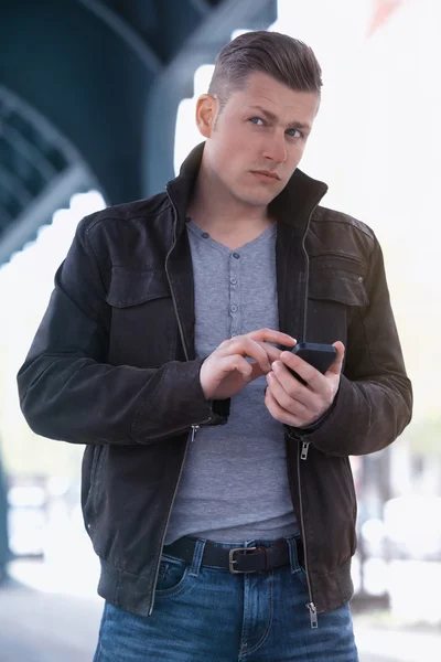 Young man in the street holding a phone — Stock Photo, Image