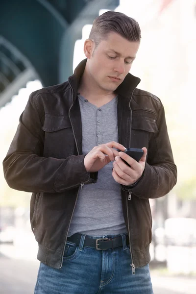 Genç adam sokakta bir telefon tutarak — Stok fotoğraf