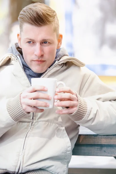 Junger Mann sitzt draußen und trinkt Kaffee — Stockfoto