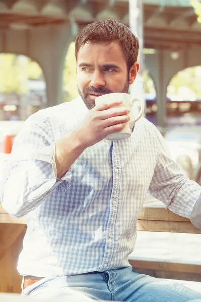 Schöner Mann sitzt draußen und trinkt Kaffee — Stockfoto