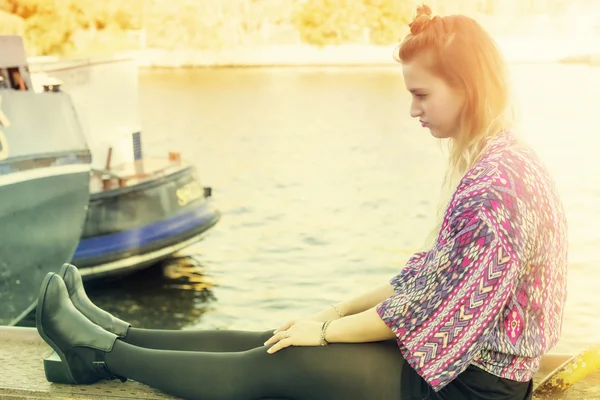 Jonge vrouw zitten door het water op zoek triest — Stockfoto