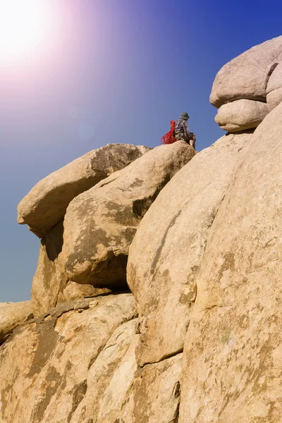 man sitting on top of rocks in the desert