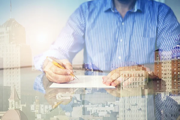 Double exposure of man at desk and cityscape — стоковое фото