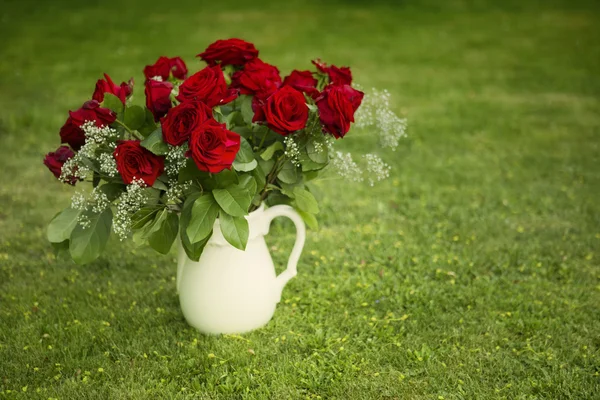 Rosas rojas en jarrón en el césped — Foto de Stock