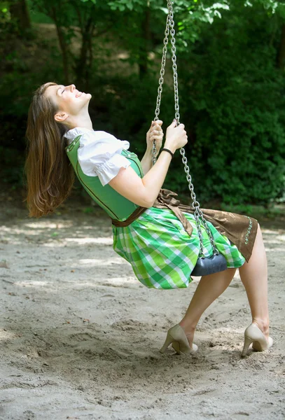 Frau im Dirndl sitzt auf Schaukel — Stockfoto