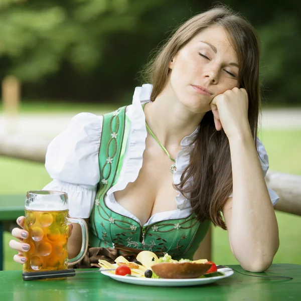 Frau im Dirndl sitzt im Biergarten und schläft — Stockfoto